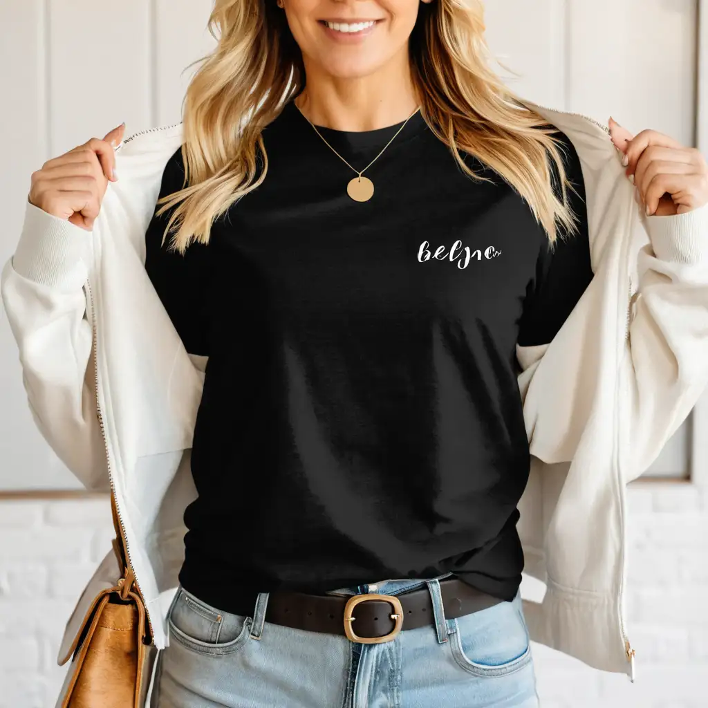 Blonde Woman in Black Bella Canvas 3001 TShirt Mockup with White Jacket in Simple Boho Home Setting