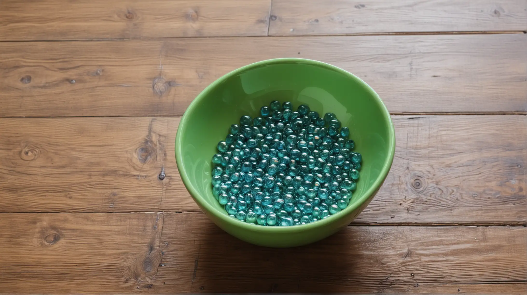 shiny green bowl with blue shiny water beads on wood floor. Close up