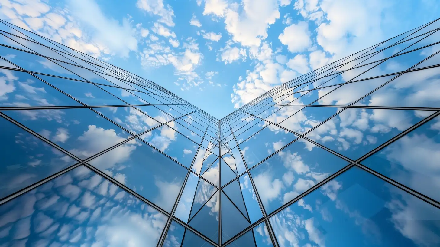 Create an image showing the upward perspective of a modern building's glass facade that reflects the blue sky and scattered clouds. The composition should focus on the sharp lines of the building’s edges and the reflective glass panels that merge seamlessly with the sky, emphasizing the interaction between architecture and nature --ar 16:9