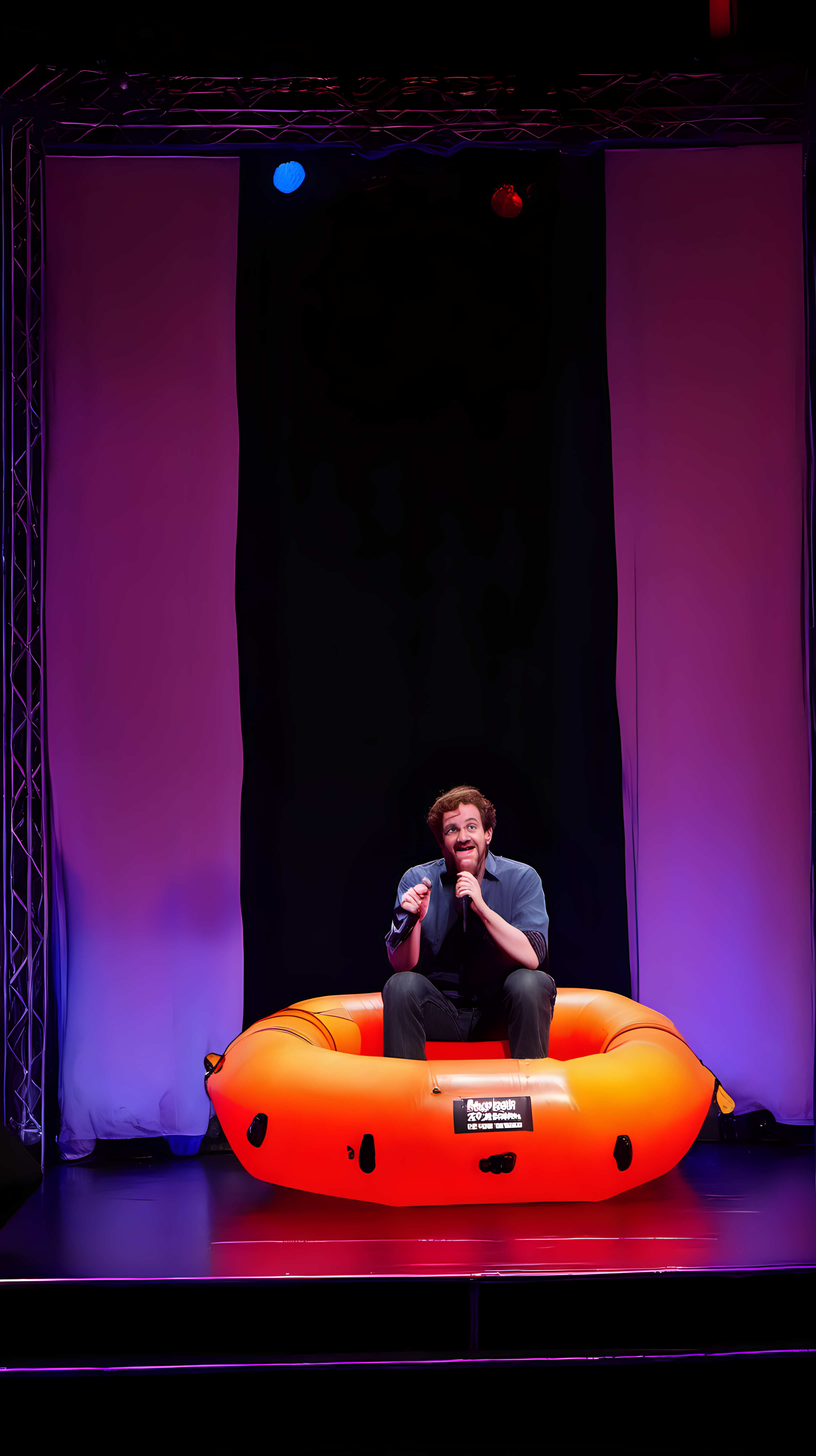 comedian on stage sitting in a rubber dingy